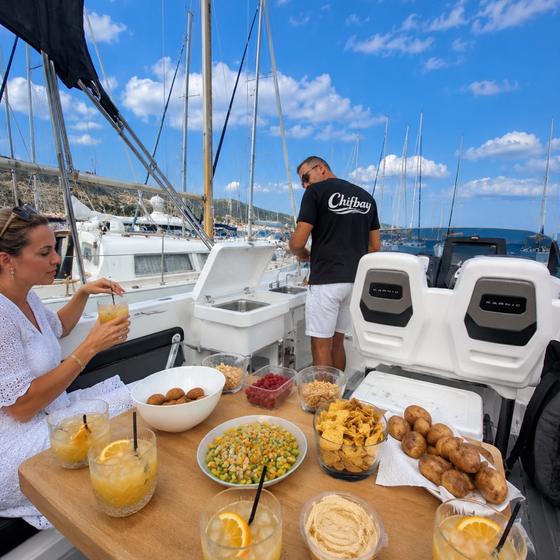 Food and drinks laid out on the deck table while the skipper looks after his guests
