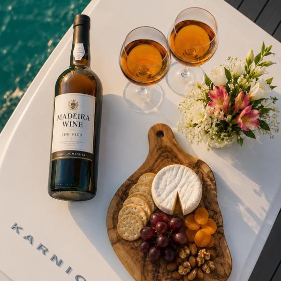 A bottle of Madeira wine, glasses and a board of local cheese laid out on the boat's table